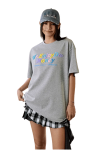 MEDM SS25 Macaron Velvet Embossed Tee in gray, styled casually with a plaid skirt and cap