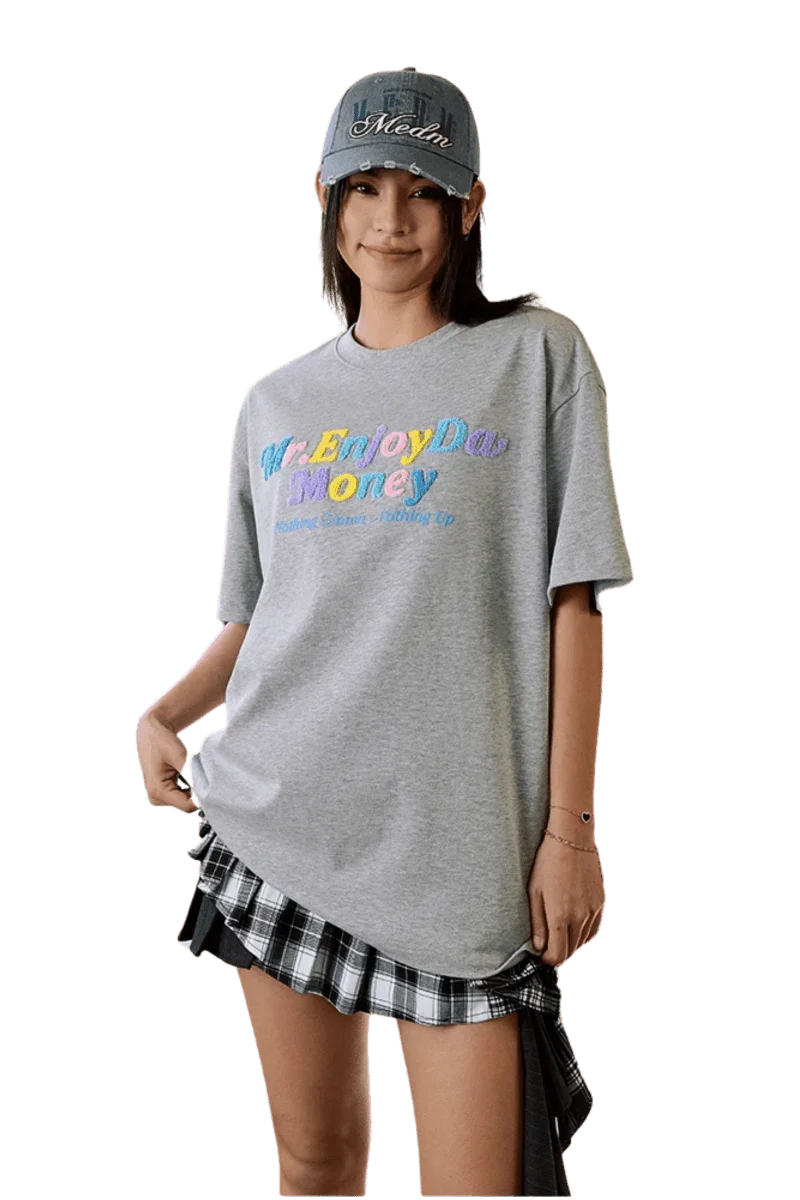 MEDM SS25 Macaron Velvet Embossed Tee in gray, styled casually with a plaid skirt and cap