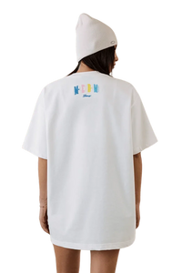 Woman wearing MEDM SS25 Macaron Velvet Embossed Tee in white, showcasing the stylish back design.