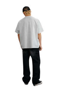 Back view of the MEDM SS25 Serendipity Embroidery Tee in light gray, stylishly paired with dark jeans