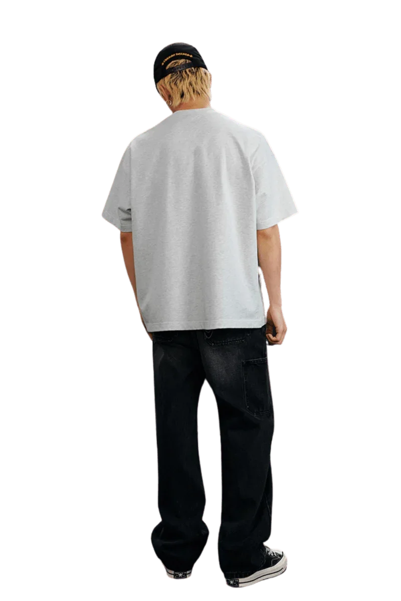 Back view of the MEDM SS25 Serendipity Embroidery Tee in light gray, stylishly paired with dark jeans