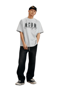 Model wearing MEDM SS25 Serendipity Embroidery Tee with casual baggy jeans and sneakers
