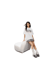 Woman wearing MEDM SS25 Serendipity Embroidery Tee with a relaxed fit, sitting on a white chair