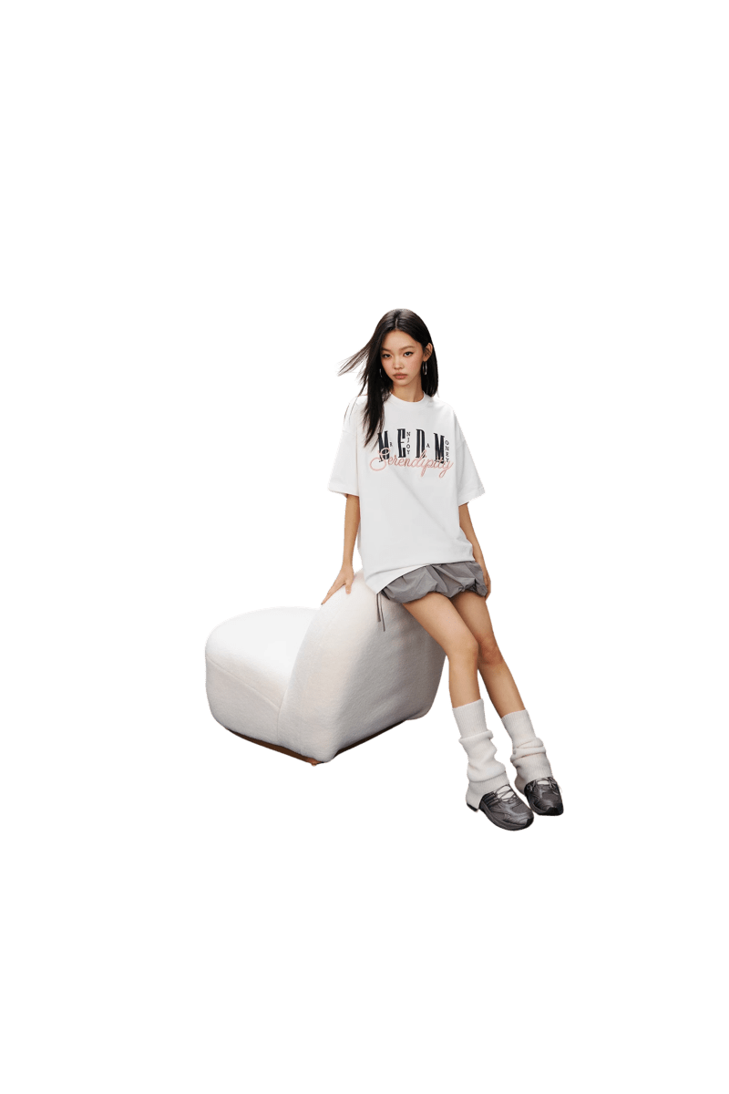 Woman wearing MEDM SS25 Serendipity Embroidery Tee with a relaxed fit, sitting on a white chair