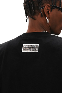 Back view of the MEDM SS25 Small Pearl Tee featuring a unique graphic detailing on a black fabric