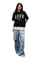 Model wearing MEDM SS25 Small Pearl Tee in black over a white shirt with distressed jeans for a casual look