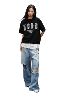 Model wearing MEDM SS25 Small Pearl Tee in black over a white shirt with distressed jeans for a casual look