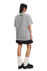 MEDM SS25 Small Pearl Tee in gray, worn with a black skirt and boots, showcasing a relaxed fit