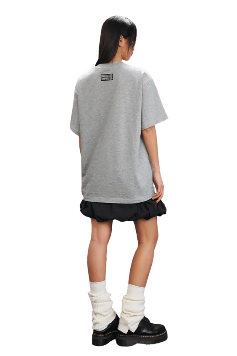 MEDM SS25 Small Pearl Tee in gray, worn with a black skirt and boots, showcasing a relaxed fit