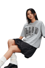 Model wearing the MEDM SS25 Small Pearl Tee in gray with graphic design and a relaxed fit