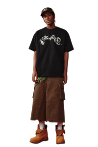 Model wearing MEDM SS25 Snake Year Limited Edition Tee with cargo shorts and stylish boots