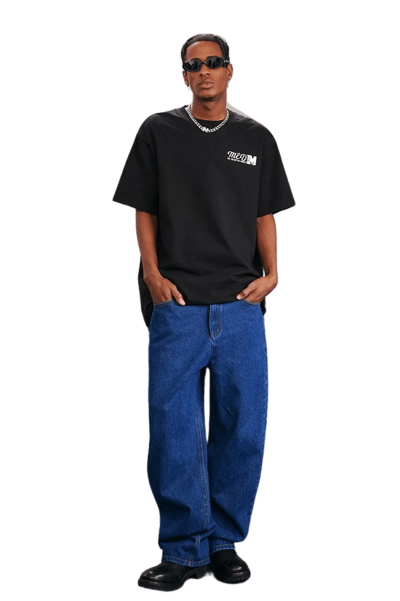 Model wearing MEDM SS25 The Time Basic Logo Tee in black with relaxed fit and blue jeans for a casual look