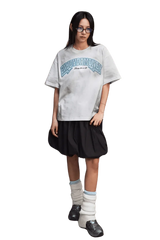 MEDM SS25 Washed Arch Logo Tee in gray on model, paired with a black skirt and stylish accessories