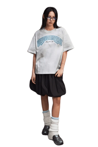 MEDM SS25 Washed Arch Logo Tee in gray on model, paired with a black skirt and stylish accessories