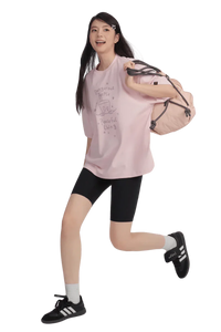 Model wearing a pink Peaceful Living Hand Painted Tee with black shorts and a backpack for a casual look