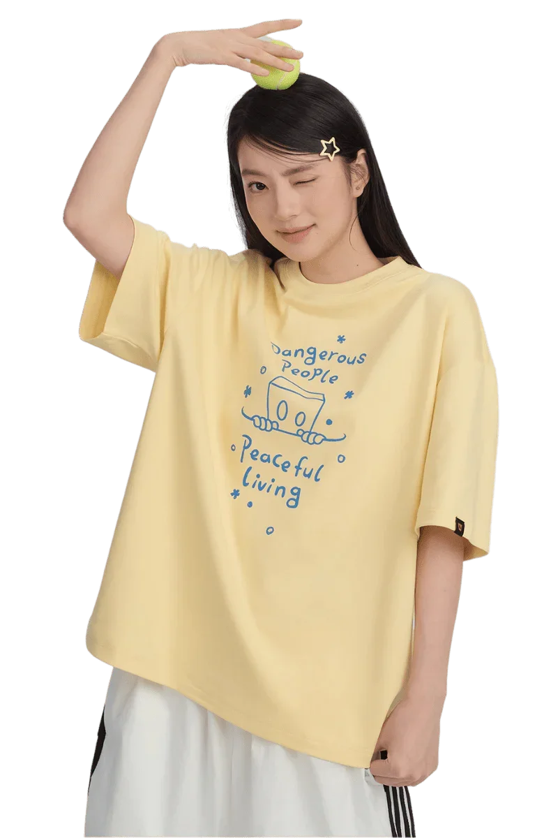 Woman wearing a yellow Dangerous People Peaceful Living Hand Painted Tee with playful graphics