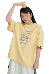 Woman wearing a yellow Dangerous People Peaceful Living Hand Painted Tee with playful graphics