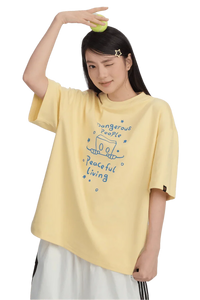 Woman wearing a yellow Dangerous People Peaceful Living Hand Painted Tee with playful graphics