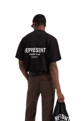 Man wearing Represent Owners Club T-Shirt in black with bold logo on back