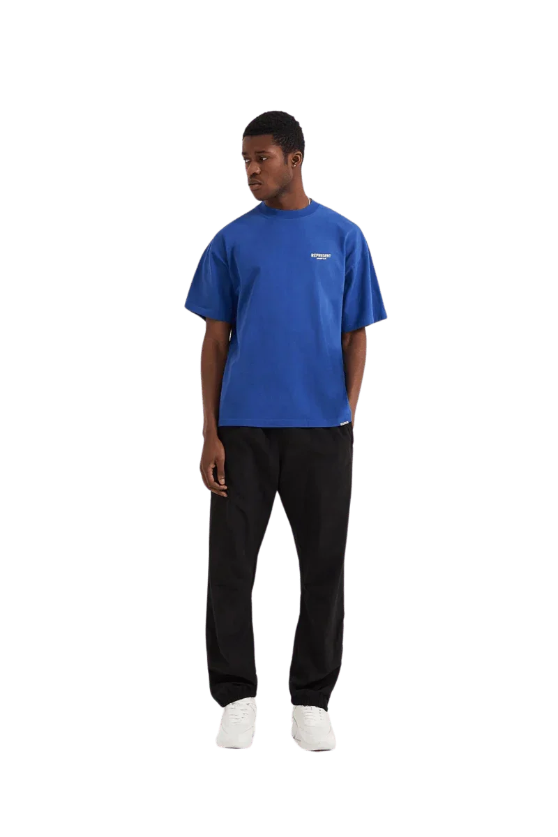 Men's blue Represent Owners Club T-Shirt styled with black pants for a casual look