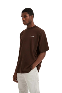 Model wearing Represent Owners Club T-Shirt in brown with relaxed fit and logo print