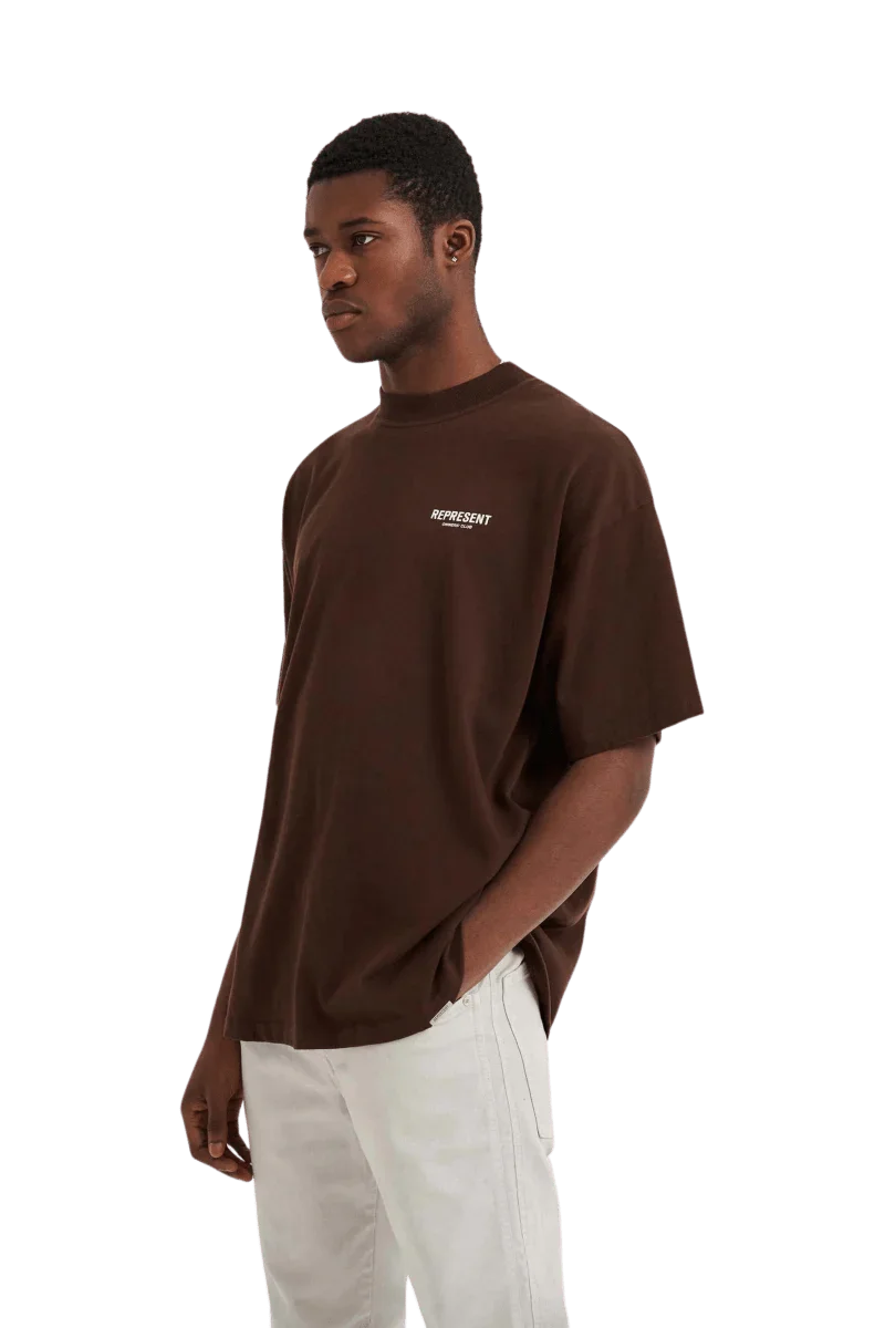 Model wearing Represent Owners Club T-Shirt in brown with relaxed fit and logo print