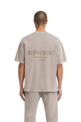 Back view of a man wearing the SS24 Owners Club Rubber Logo T-Shirt in light gray with bold logo design