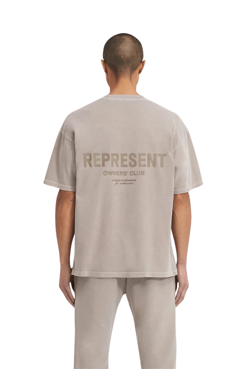 Back view of a man wearing the SS24 Owners Club Rubber Logo T-Shirt in light gray with bold logo design