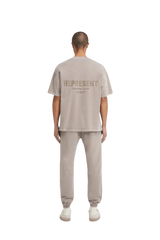 Back view of SS24 Owners Club Rubber Logo T-Shirt in light gray by Represent, styled with matching joggers