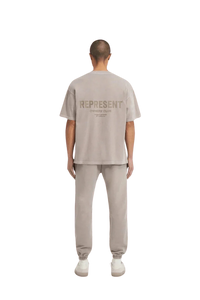 Back view of SS24 Owners Club Rubber Logo T-Shirt in light gray by Represent, styled with matching joggers