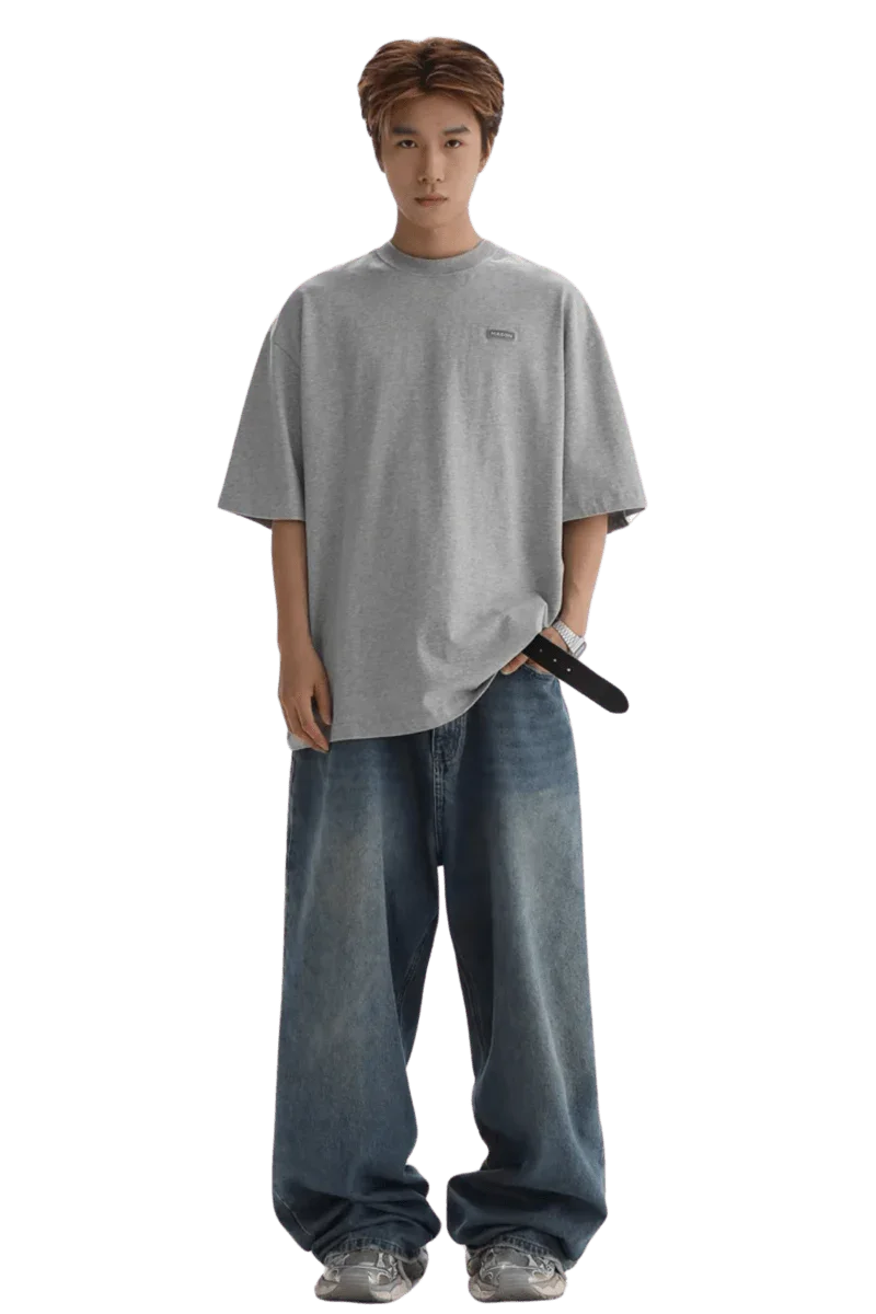Masonprince Small Logo Basic Tee in gray worn with loose blue jeans and sneakers on male model