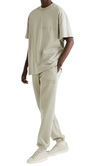 Men's Fear Of God Essentials FW22 Flock Logo Tee in beige, styled with matching pants and sneakers