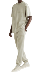 Men's Fear Of God Essentials FW22 Flock Logo Tee in beige, styled with matching pants and sneakers