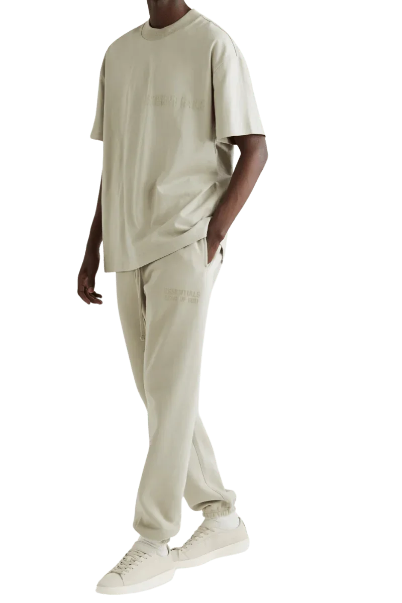 Men's Fear Of God Essentials FW22 Flock Logo Tee in beige, styled with matching pants and sneakers