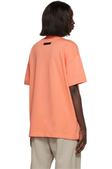 Fear Of God Essentials FW22 Flock Logo Tee in vibrant orange color with a relaxed fit